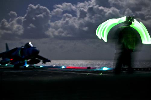 A U.S. Navy sailor guides an AV-8B Harrier