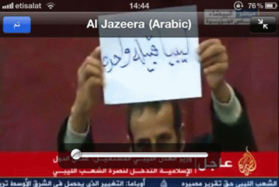 Man holding up to TV camera sign that reads &quot;Libya is one tribe&quot; during tribal leaders meeting in Bayda now 