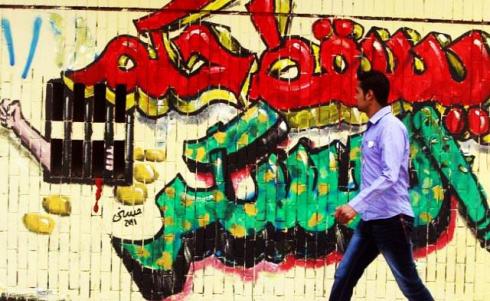 An Egyptian walks past graffiti which reads “Down with the military rule” during clashes between protesters and riot police at Tahrir Square in Cairo Nov.19, 2011.(Reuters)