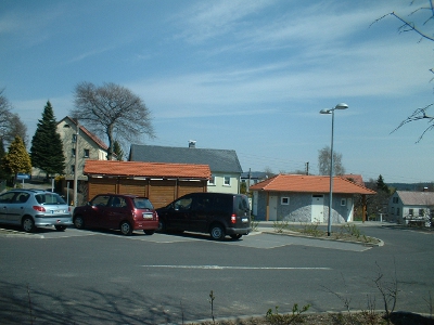 betonierter Kroneplatz in Steina mit Parkplatz, Toilette und Bushaltestelle am Standort des einstigen Dorfgasthofs